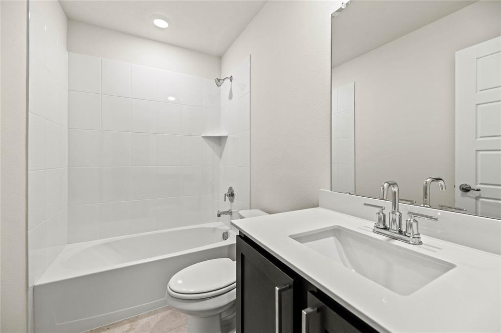 411 Revolution Road Fate, TX 75087 - Photo 16 of 34 a bathroom with a sink a toilet and a large mirror