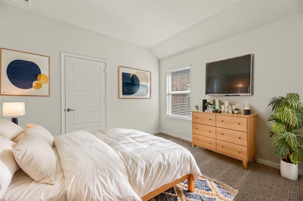 411 Revolution Road Fate, TX 75087 - Photo 19 of 34 a bedroom with a bed potted plant and a flat screen tv