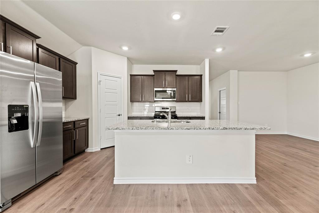 411 Revolution Road Fate, TX 75087 - Photo 20 of 34 a kitchen with stainless steel appliances granite countertop a sink a stove a refrigerator and cabinets