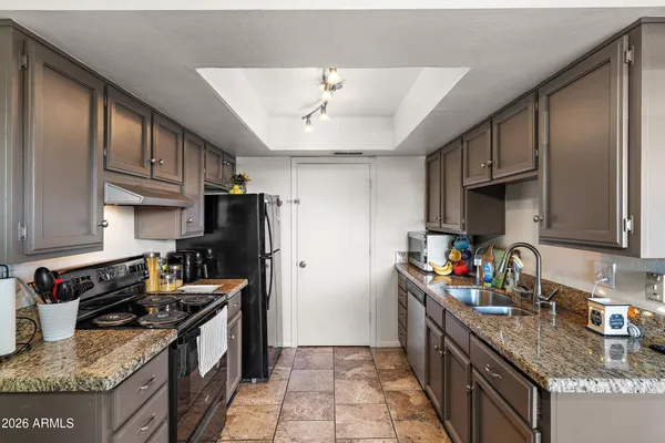 a kitchen with granite countertop a refrigerator stove and sink