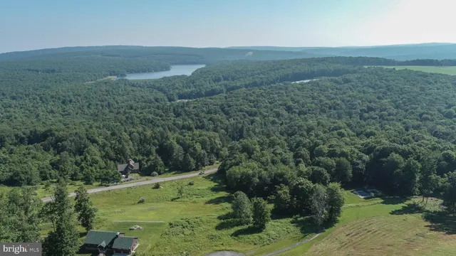 an aerial view of a house with yard and trees in the background