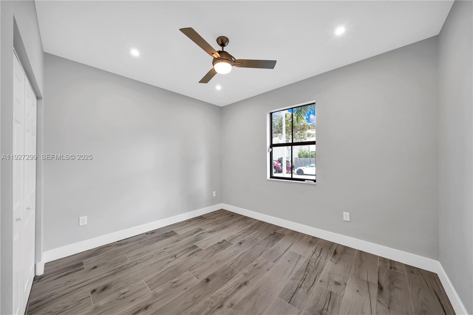 11448 Southwest 151st Path Miami, FL 33196 - Photo 13 of 35 an empty room with wooden floor ceiling fan and windows