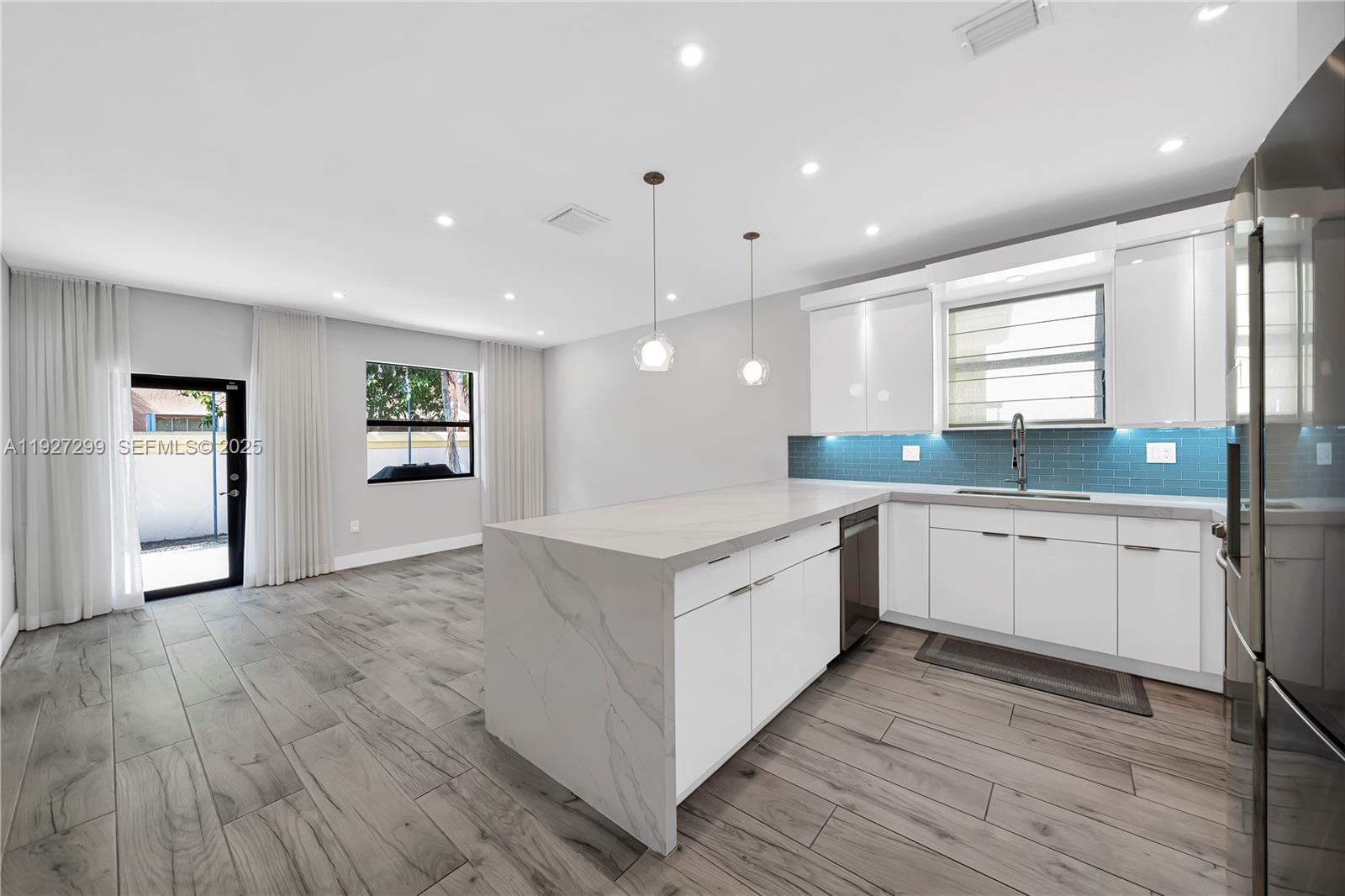 11448 Southwest 151st Path Miami, FL 33196 - Photo 28 of 35 a large white kitchen with granite countertop a stove top oven a sink and white cabinets with wooden floor