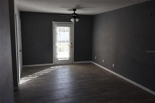 a view of an empty room with wooden floor and a window