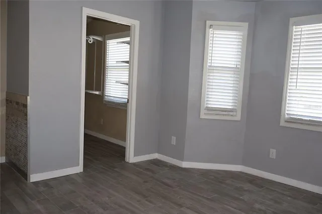 an empty room with wooden floor closet and windows