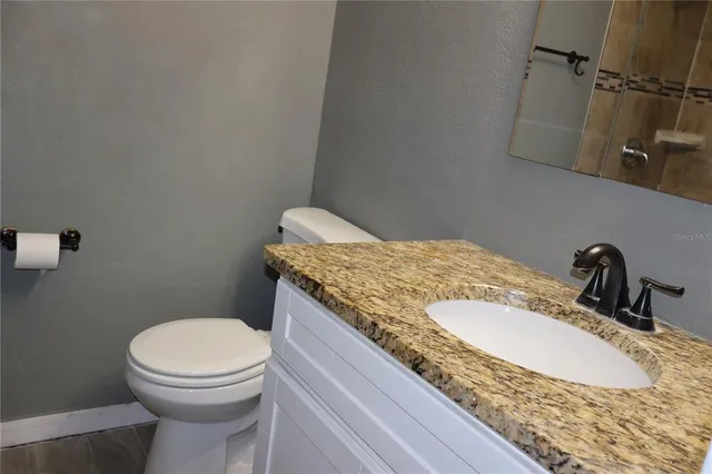 a bathroom with a granite countertop sink and a toilet