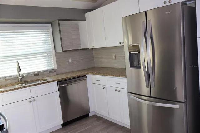 a kitchen with stainless steel appliances granite countertop a refrigerator and a sink