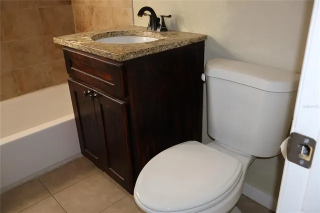a bathroom with a granite countertop toilet sink and mirror