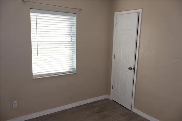a view of an empty room with wooden floor and a window