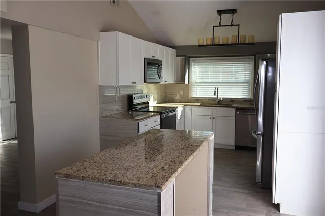 a kitchen with stainless steel appliances granite countertop a sink a stove and a refrigerator