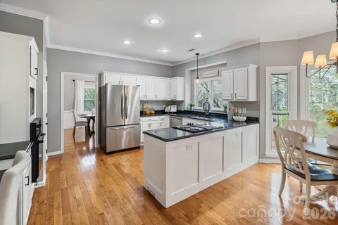 a kitchen with granite countertop a stove a sink a refrigerator and wooden floor
