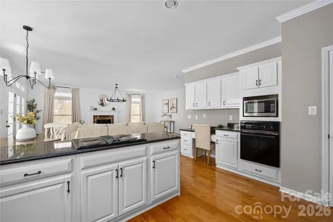 a kitchen with stainless steel appliances granite countertop a stove a sink and a white cabinets