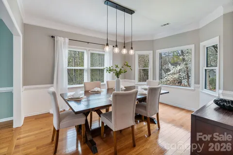 a dining room with wooden floor a chandelier a wooden table and chairs
