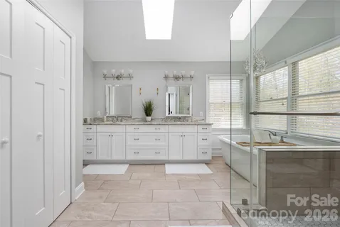 a bathroom with double vanity sinks a large mirror and a bath tub