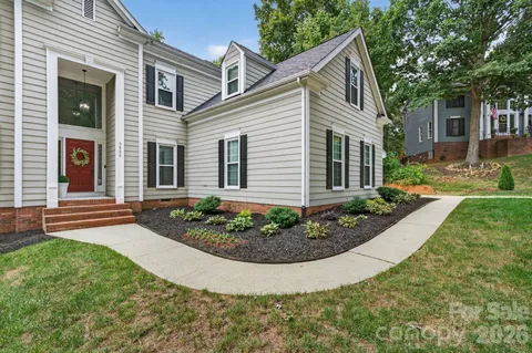 a view of a white house with a small yard and large tree
