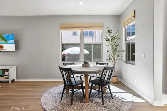 a kitchen with stainless steel appliances kitchen island granite countertop a sink a refrigerator a stove and white cabinets with wooden floor