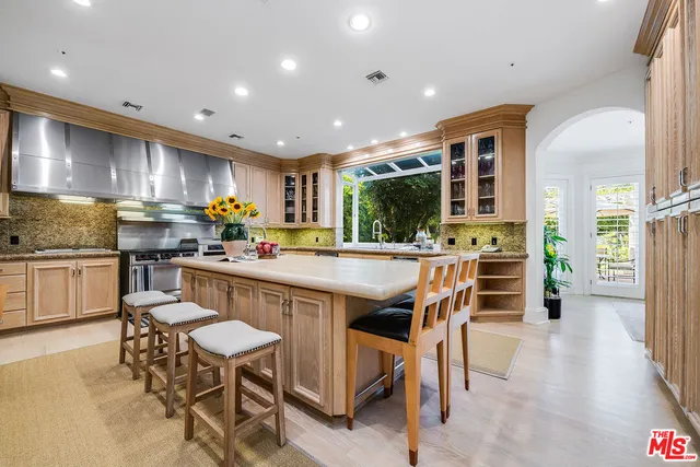 a kitchen with stainless steel appliances kitchen island granite countertop a table chairs sink and cabinets