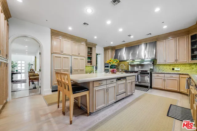 a kitchen with stainless steel appliances granite countertop a stove top oven a sink dishwasher a dining table and chairs with wooden floor