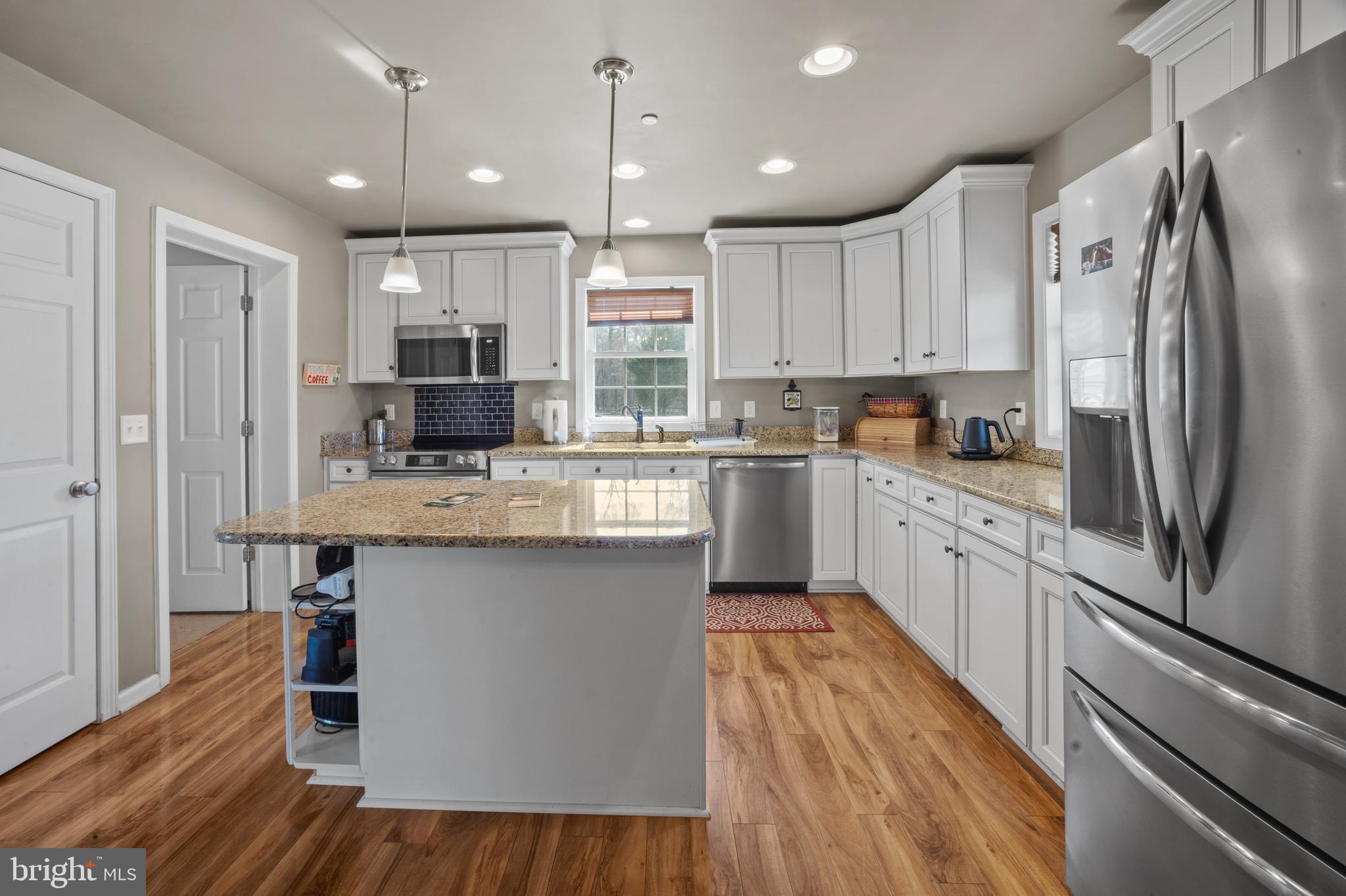 26268 Baker Road Denton, MD 21629 - Photo 3 of 55 a kitchen with stainless steel appliances granite countertop a refrigerator a sink dishwasher a stove and white countertops with wooden floor