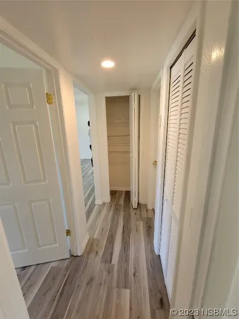 a view of a hallway with wooden floor and closet area
