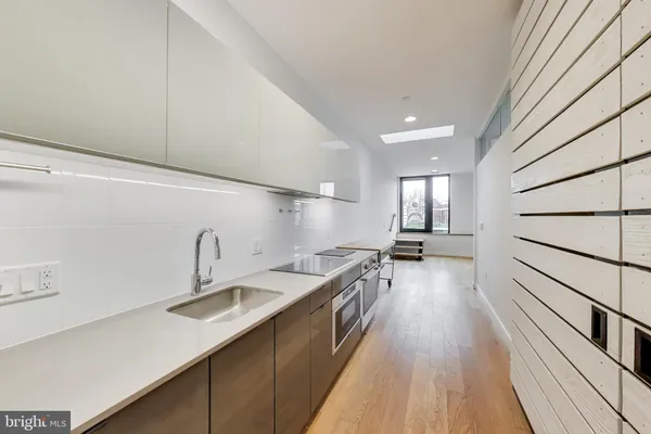 a kitchen with granite countertop a sink a counter space appliances and cabinets
