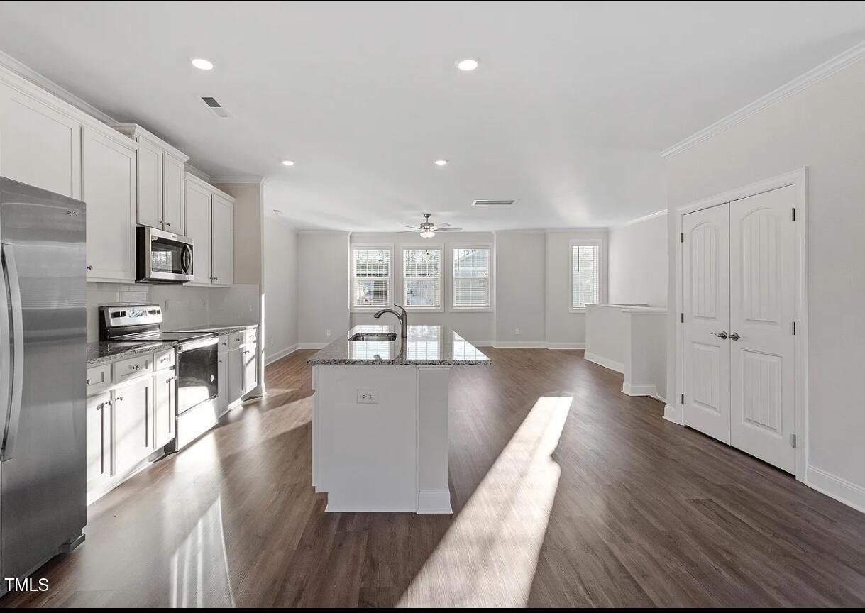 6914 Woodland Stream Place Raleigh, NC 27616 - Photo 1 of 12 a view of a kitchen with kitchen island granite countertop wooden floors and stainless steel appliances