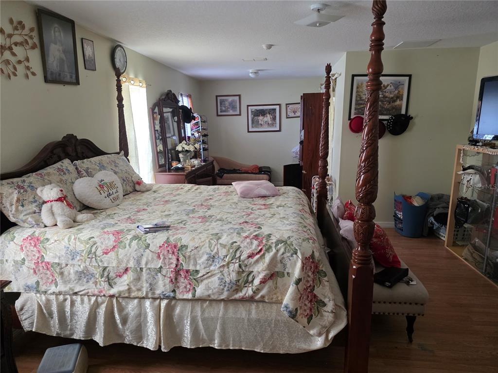 4671 Southwest 100th Lane Ocala, FL 34476 - Photo 7 of 8 a bedroom with a bed and wooden floor