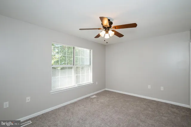 an empty room with a window and a fan