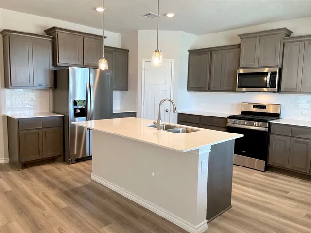 a kitchen with stainless steel appliances a sink stove refrigerator and cabinets