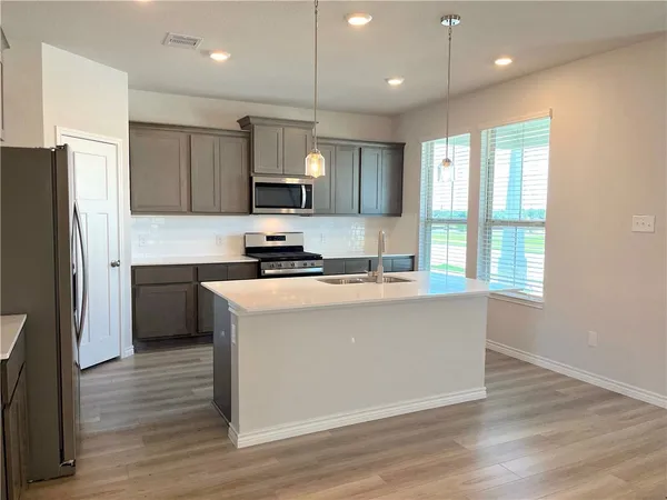 a kitchen with stainless steel appliances granite countertop a refrigerator a sink a stove a microwave and wooden floor