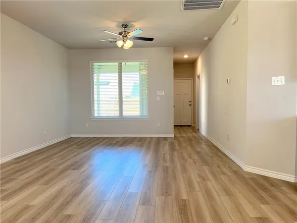 a view of an empty room with a window and wooden floor