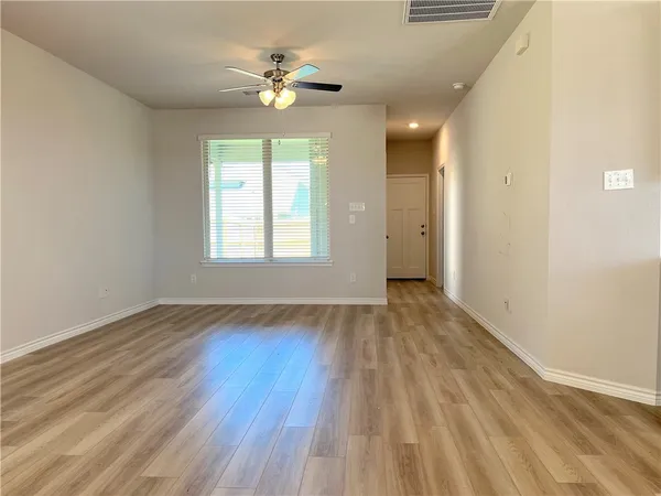 a view of an empty room with a window and wooden floor