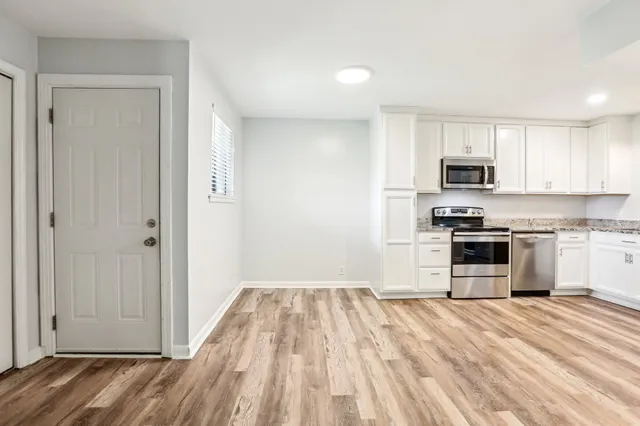 a view of a kitchen with refrigerator and wooden floor