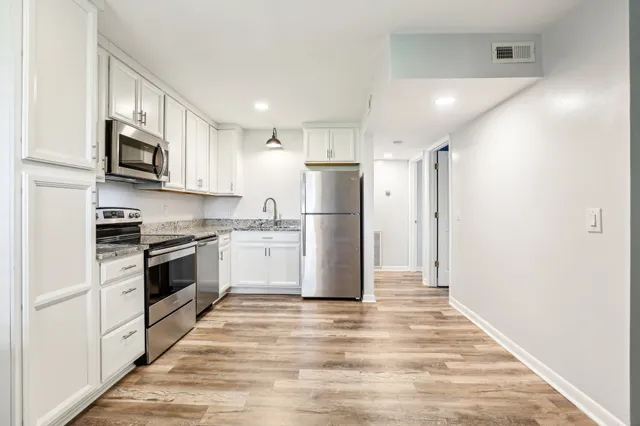 a kitchen with white cabinets stainless steel appliances and a refrigerator