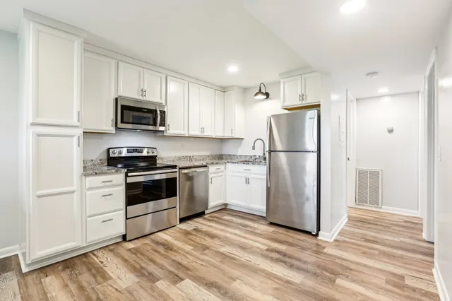 a kitchen with white cabinets stainless steel appliances and wooden floor