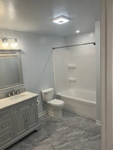 an empty room with wooden floor ceiling fan and windows