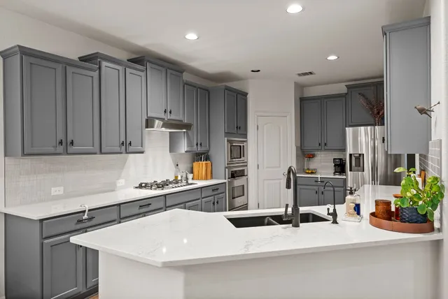 a kitchen with stainless steel appliances kitchen island granite countertop a sink a stove and a refrigerator
