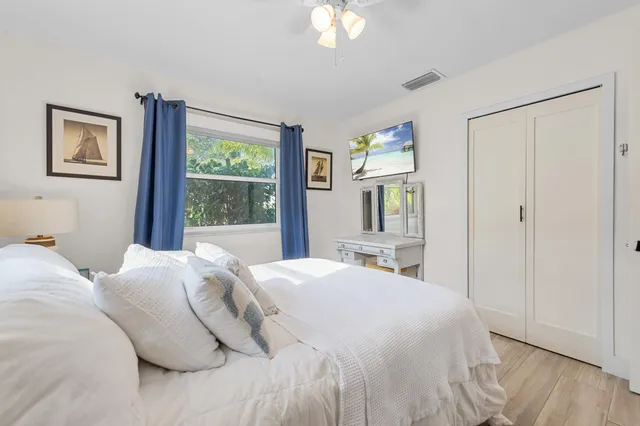 a bedroom with a bed painting on wall and a large window