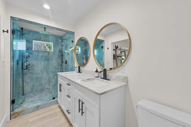 a bathroom with a granite countertop sink a mirror and a shower