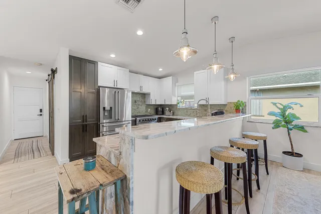 a kitchen with stainless steel appliances kitchen island a refrigerator and chairs