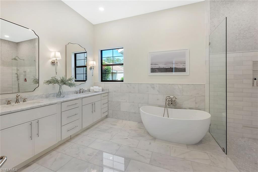 981 Tierra Lago Way Naples, FL 34119 - Photo 25 of 49 a spacious bathroom with a double vanity sink mirror and bathtub