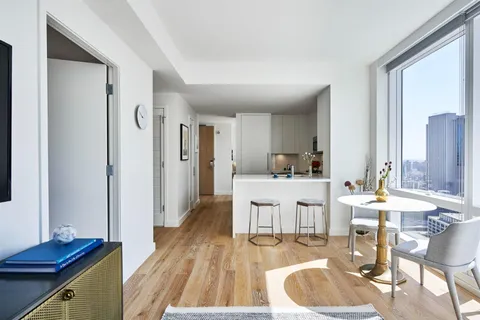 a living room with stainless steel appliances kitchen island granite countertop furniture and a wooden floor