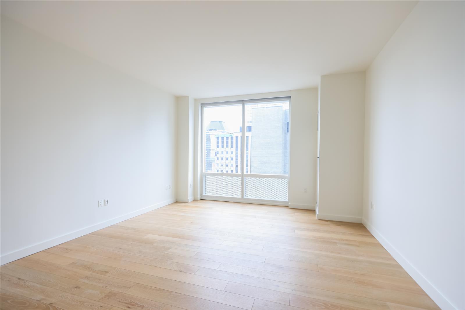 19 Dutch Street, Unit 50H Manhattan, NY 10038 - Photo 4 of 36 a view of an empty room with wooden floor and a window