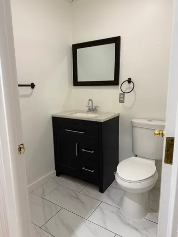 a bathroom with a toilet sink vanity and mirror