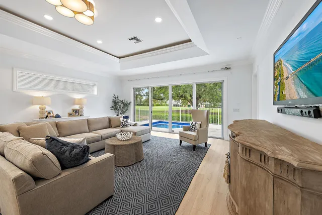 a kitchen with stainless steel appliances kitchen island granite countertop a sink a stove a refrigerator and white cabinets with wooden floor