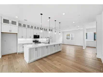 a large white kitchen with lots of counter space wooden floor and stainless steel appliances