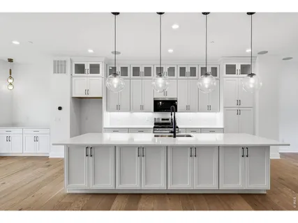 a kitchen with kitchen island granite countertop a sink a stove and cabinets