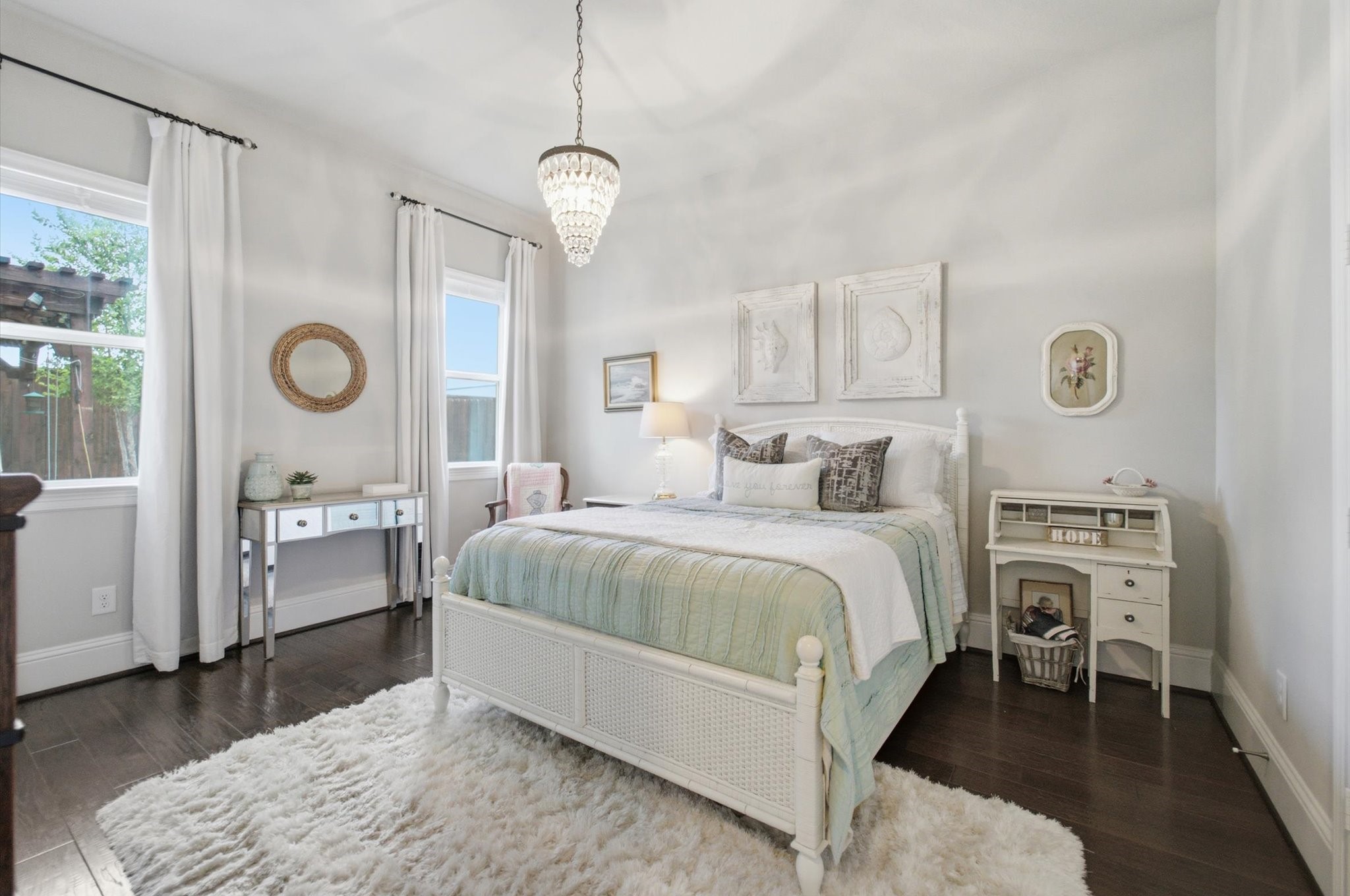 23722 Thortons Park Lane Spring, TX 77389 - Photo 19 of 48 This is a bright, inviting bedroom featuring a large window, hardwood floors, and a soft area rug. The room is tastefully decorated with a cozy bed, elegant chandelier, and a chic desk, creating a serene and stylish atmosphere.