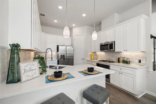 a kitchen with white cabinets and appliances
