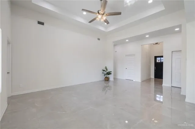 an empty room with fan and a kitchen view